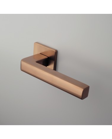 Poignée de porte cuivre SALICE quincaillerie design montée sur une porte