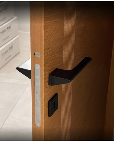 Poignée de porte noire LUPINA poignée design montée sur une porte entrouverte
