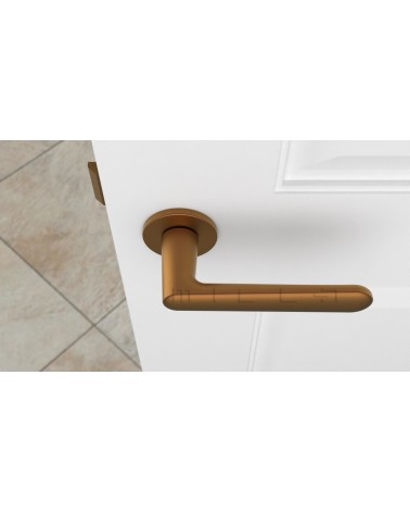 Poignée de porte cuivre ARIA poignée design vue de haut montée sur une porte