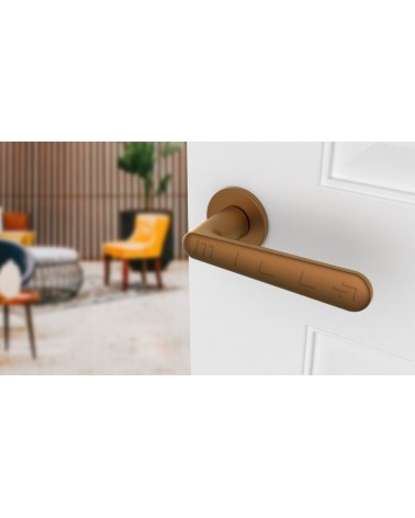 Poignée de porte cuivre ARIA poignée design vue de haut inclinée montée sur une porte