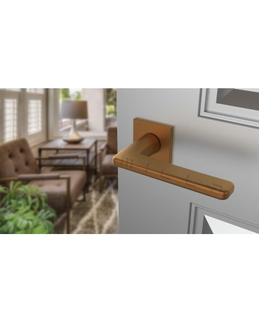 Poignée de porte cuivre SETIA poignée design vue de haut inclinée montée sur une porte