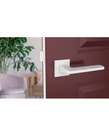 Poignée de porte blanche YUKA quincaillerie design vue de face montée sur une porte