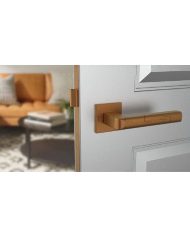 Poignée de porte cuivre SALICE quincaillerie design vue de face montée sur une porte