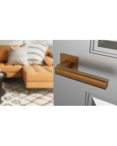 Poignée de porte cuivre SALICE quincaillerie design vue inclinée montée sur une porte