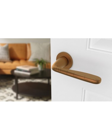 Poignée de porte cuivre HIACYNTA poignée design vue de haut inclinée montée sur une porte