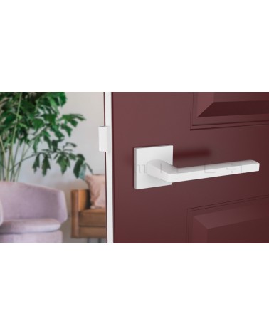 Poignée de porte blanche PYROLA quincaillerie design montée sur une porte entrouverte
