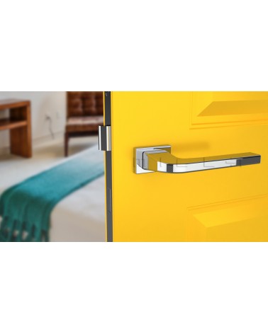 Poignée de porte chrome poli ISMENA quincaillerie design vue de face montée sur une porte