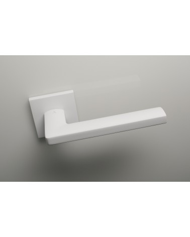Poignée de porte blanche PYROLA quincaillerie design vue de haut légèrement inclinée montée sur une porte