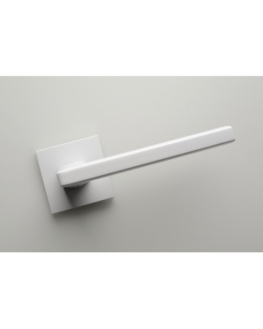 Poignée de porte blanche PYROLA quincaillerie design vue de face inclinée montée sur une porte