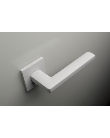 Poignée de porte blanche PYROLA quincaillerie design vue de haut poignée inclinée vers le haut montée sur une porte