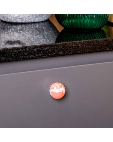 Bouton de meuble en bois de hêtre rouge cerise poignée design vue rapproché montée sur un meuble de cuisine