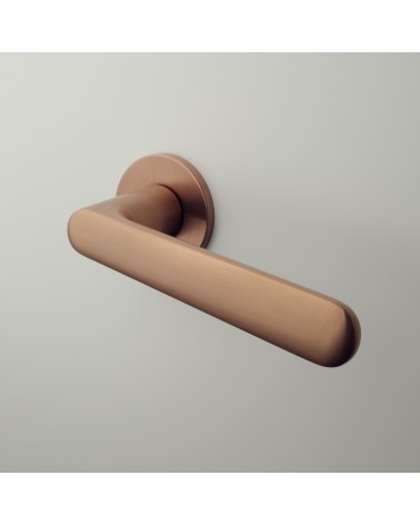 Poignée de porte cuivre ARIA poignée design montée sur une porte