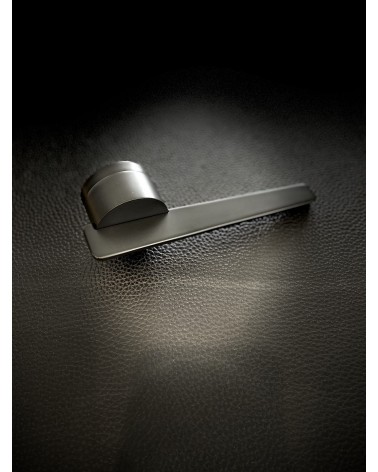 Poignée de porte noire JUMELLE poignée design posée sur un fond sombre