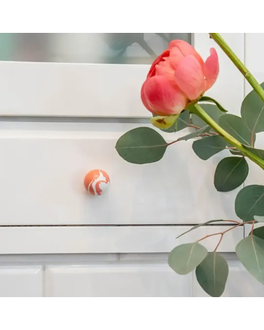 Bouton de meuble en bois de hêtre rouge cerise poignée design monté sur un meuble accompagné d'une rose posée dessus