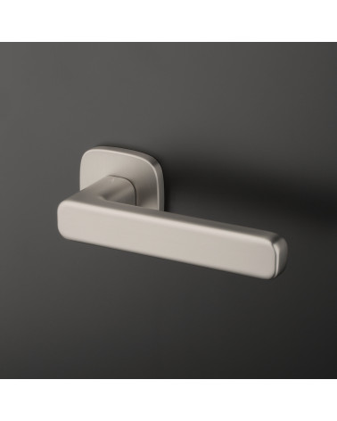 Poignée de porte nickel satiné IXIA poignée design fixée sur un fond sombre