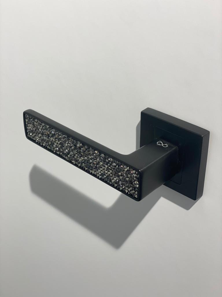 Poignée de porte noire mate avec strass sur la béquille sur une porte blanche pour accentuer le contraste