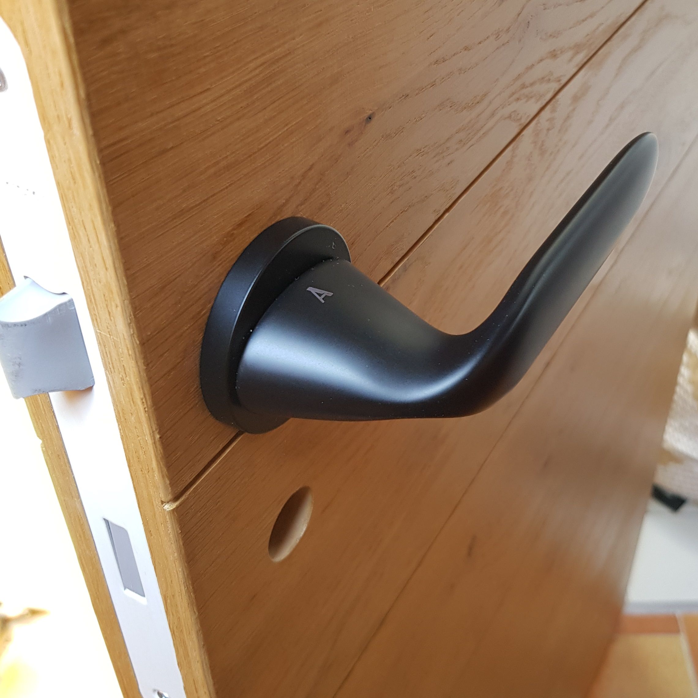 poignée de porte moderne noire installée sur une porte finition aspect bois