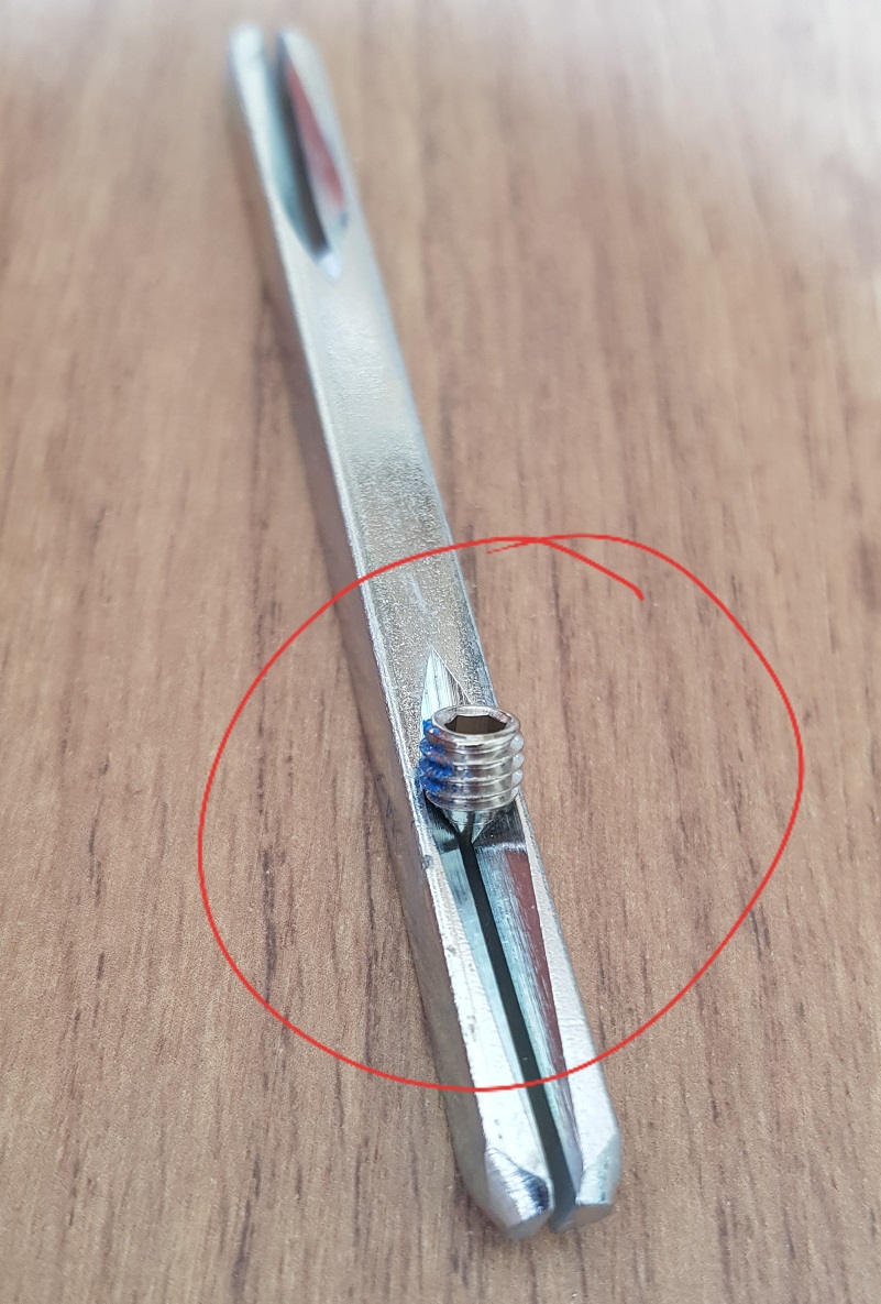 tige carrée de 7mm pour poignée de porte avec une vis pointeau entouré sur le fond en bois