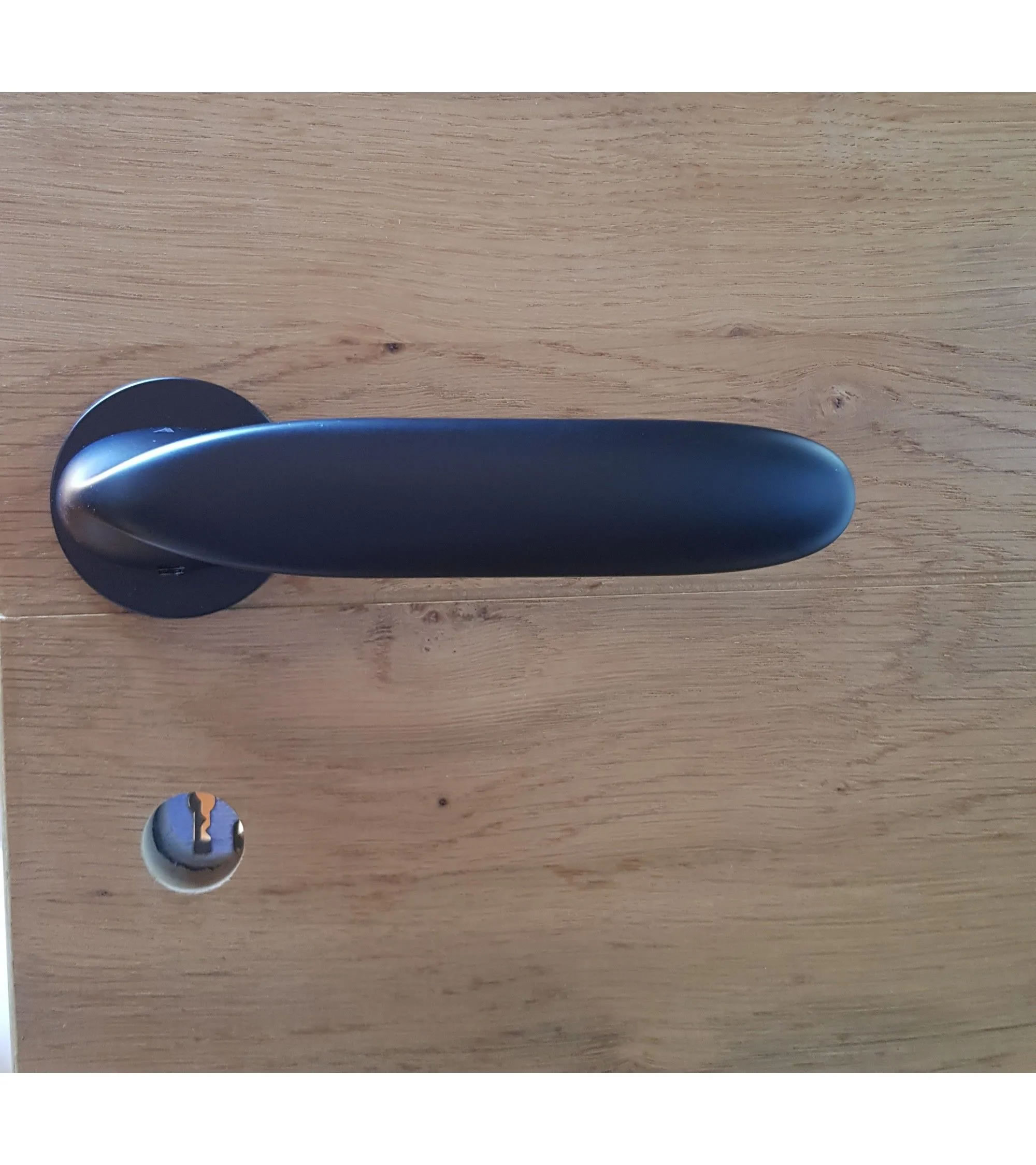 poignée de porte noire sur une porte en bois claire vendue par mille poignées
