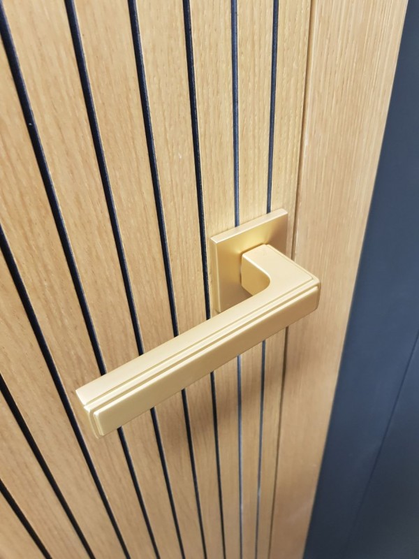 poignée de porte dorée mat sur une porte en bois